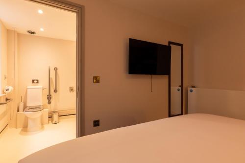 a bedroom with a bathroom with a toilet and a television at Offshore - The Inn Collection Group in Lytham St Annes