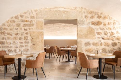 un restaurant avec des tables et des chaises et un mur de pierre dans l'établissement Domaine et Château de Valinches, à Marols