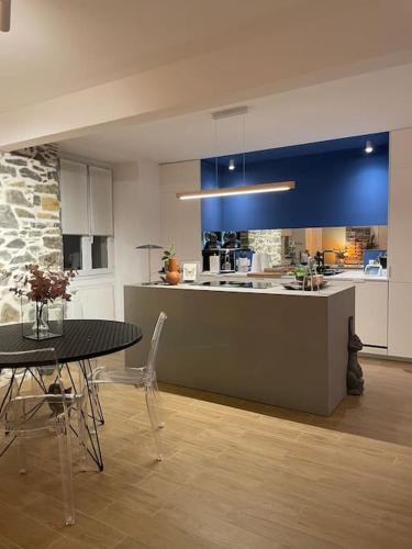 une cuisine avec une table et une cuisine aux murs bleus dans l'établissement Élégant 2 chambres à deux pas de l'Espagne, à Urrugne