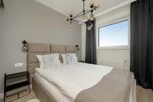a bedroom with a large white bed with a window at Exclusive River View Apartment with Balcony & FREE GARAGE by Renters Prestige in Wrocław