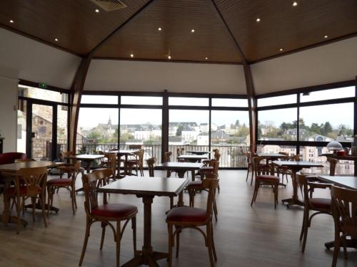 un restaurante con mesas, sillas y ventanas en Hôtel La Tour des Anglais, en Mayenne
