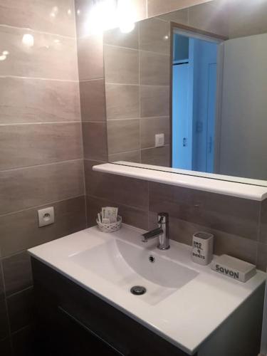 une salle de bain avec un lavabo et un miroir dans l'établissement T3 classé 3 * vue mer parking 100 m plage/ville, au Lavandou