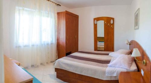 a small bedroom with a bed and a mirror at Apartments in Lopar - Insel Rab 26467 in Lopar