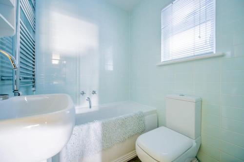 een witte badkamer met een toilet en een wastafel bij Family Haven by the Waves Direct Beach Access in Pevensey