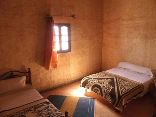 una camera con due letti e una finestra di Hostel la palmeraie merzouga a Merzouga
