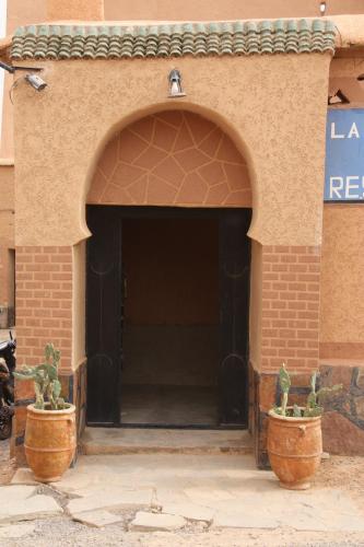 an entrance to a building with two large pots at La perle de saghro in Nkob