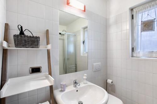 a white bathroom with a sink and a mirror at Alpen Pila Residence Loft 7 in Aosta
