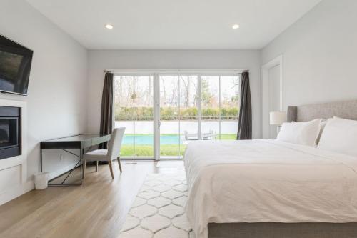 a bedroom with a bed and a desk and a window at Villa Kimaal - Luxury with pool in Sag Harbor