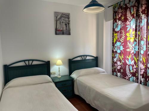 two twin beds in a room with two lamps and curtains at ÁTICO FRONTAL AL MAR, TRES DORMITORIOS EN ALCAUDÓN in Isla Canela