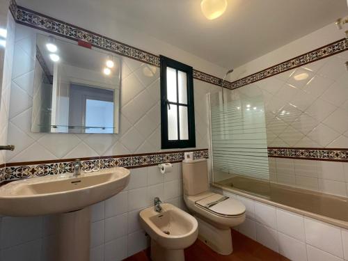 a bathroom with a sink and a toilet and a mirror at ÁTICO FRONTAL AL MAR, TRES DORMITORIOS EN ALCAUDÓN in Isla Canela
