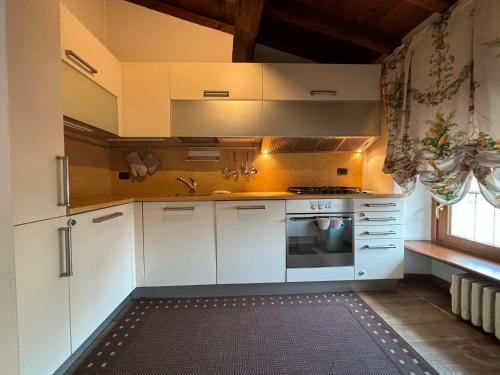 una cucina con armadietti bianchi e piano cottura di Piazza Erbe Lodge a Verona