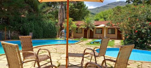 - une terrasse avec des chaises et un parasol à côté de la piscine dans l'établissement Pousada Estalagem Moeda Real, à Moeda