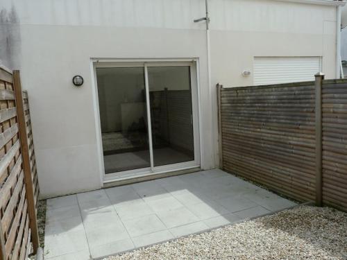 un patio con una puerta corredera de cristal en un edificio en Petite maison avec jardin en La Rochelle