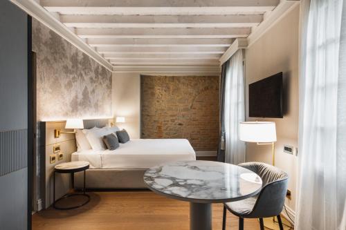 a hotel room with a bed and a table at Villa Santa Maria Maddalena by Palazzo di Varignana in Casalecchio deʼ Conti