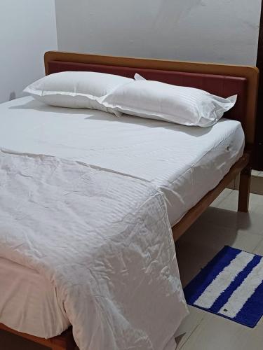 een bed met witte lakens en kussens erop bij River Valley in Mananthavady