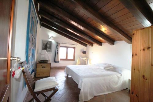 ein Schlafzimmer mit einem weißen Bett und einem Stuhl in der Unterkunft Villa Le Saline Ampia Vista Mare in Palau
