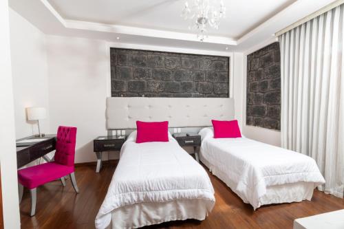 a bedroom with two beds and a desk and a chair at Sangay Spa Hotel in Baños