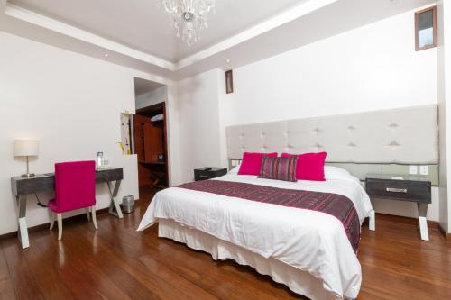 a white bedroom with a large bed with pink pillows at Sangay Spa Hotel in Baños