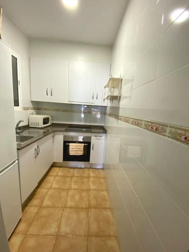 cocina con armarios blancos y suelo de baldosa en Casa Benicassim Completa en Benicàssim