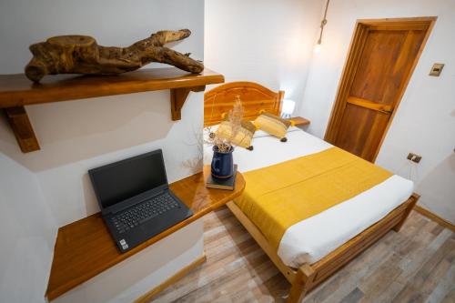 Schlafzimmer mit einem Bett und einem Laptop auf einem Schreibtisch in der Unterkunft Hotel Don Raul in San Pedro de Atacama