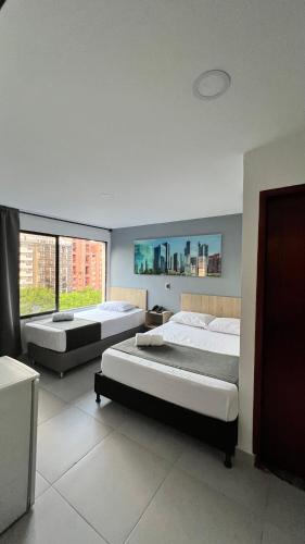 a bedroom with three beds and a large window at Hotel Gran Conquistador 33 in Medellín