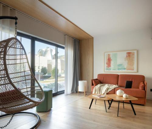 Apartamentos Líbere Bilbao Museo في بلباو: غرفة معيشة مع أريكة ومرجيح