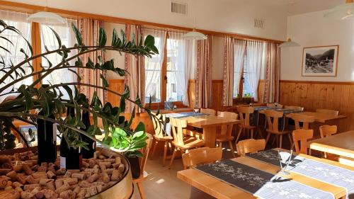 um restaurante com mesas e cadeiras e um vaso de plantas em Gasthaus Alpenrose em Innerferrera