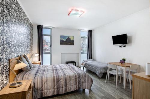 um quarto de hotel com uma cama, uma secretária e uma televisão em Alpen Pila Residence Loft 1 em Aosta