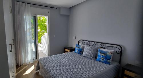 a bedroom with a bed with blue pillows and a window at Beachfront Bliss in Kardamaina