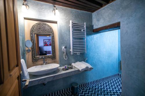 a blue bathroom with a sink and a mirror at Riad Jamal in Fez