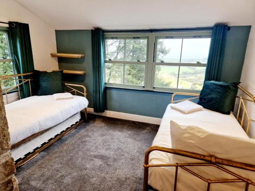 Wheal Tor Hotel & Glamping في ليسكيرد: سريرين في غرفة بها نافذتين