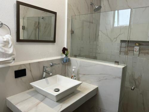 uma casa de banho branca com um lavatório e um chuveiro em Villas Carlota Cancún em Cancún