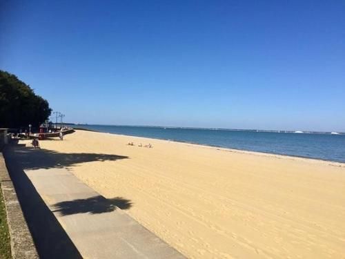 a beach with people sitting on the sand and the ocean at NEW The Old Drill Hall 4 in Ryde