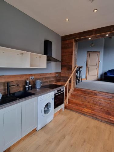 a kitchen with white cabinets and a washer and dryer at Apartment 3 The Old Drill Hall in Ryde