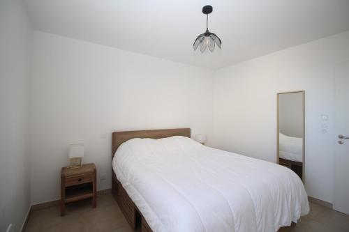 une chambre blanche avec un lit et un miroir dans l'établissement Appartement 2 chambres, vue mer et parking, à Canet