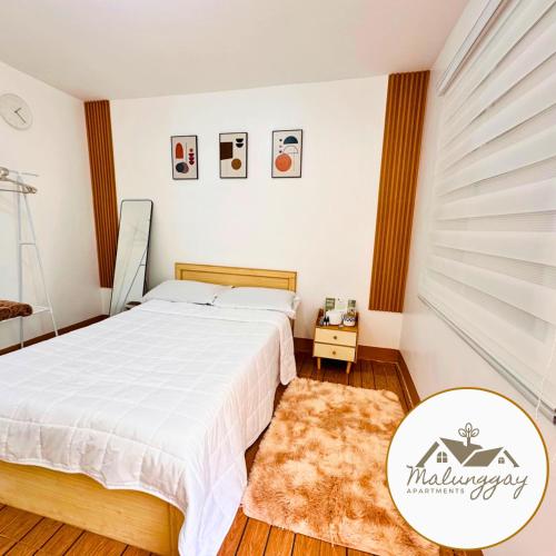 um quarto com uma cama branca e um tapete em Malunggay Apartments em Mariveles