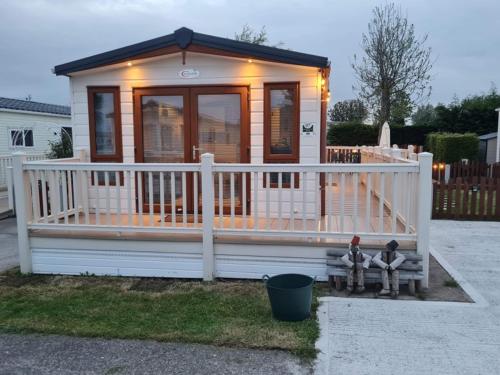 a small house with a white fence and a porch at 2 Bed Lodge Style Caravan with Hot Tub & Private Garden in Patrington