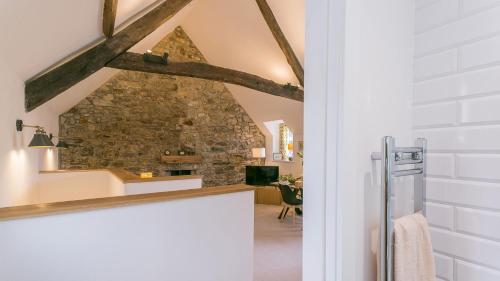 a kitchen with a stone wall and a table at Custom Mews in Beaumaris
