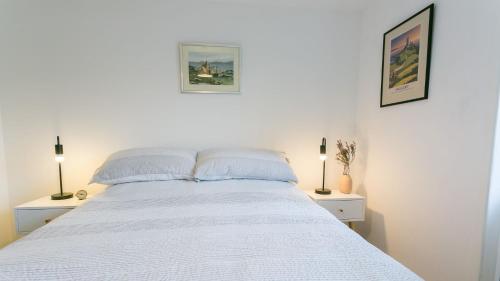 a bedroom with a white bed with two lamps at Custom Mews in Beaumaris