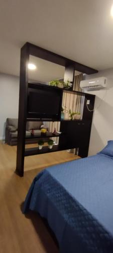 a bedroom with a bed and a flat screen tv at Flat Santa Cruz do Sul III in Santa Cruz do Sul