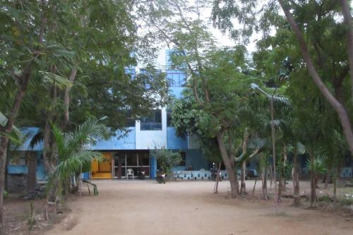 een blauw gebouw met bomen ervoor bij HOTEL SIVA SAKTHI in Tiruvannamalai