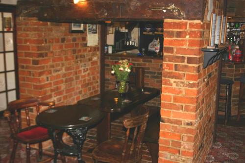 ThaxtedにあるFarmhouse Innのレンガ壁の客室で、テーブルと椅子が備わります。
