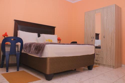 a bedroom with a large bed and a blue chair at Luma Guest House in Kasane