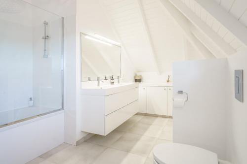 a white bathroom with a sink and a toilet at Luxe pleine vue mer et plage in Saint-François