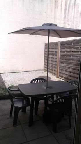 une table avec un parasol et deux chaises dans l'établissement Petite maison avec jardin, à La Rochelle