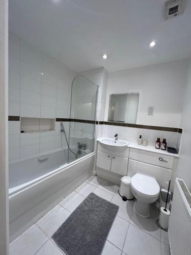 a bathroom with a toilet and a tub and a sink at Centrally Located Flat in London with Free Parking in Edgware