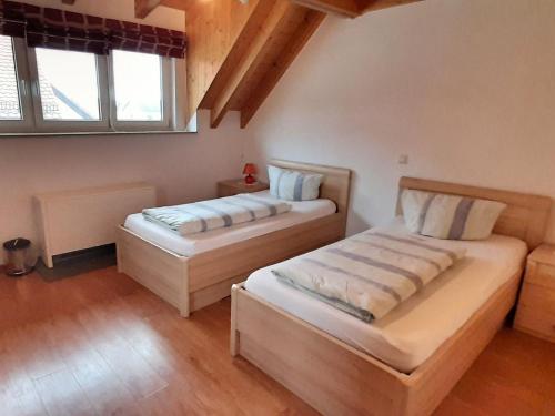 two beds in a room with two windows at Gästehaus Ritter in Sinsheim