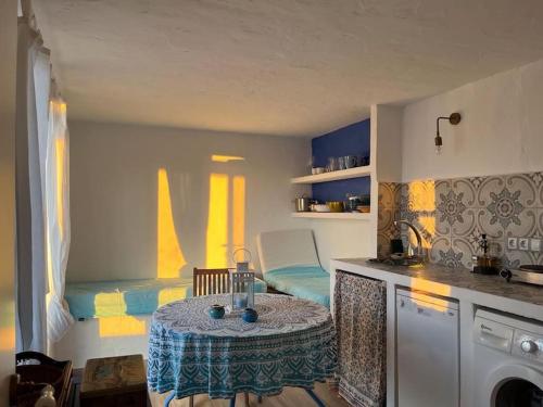 uma cozinha com uma mesa e uma cama num quarto em CASITA LINDA em Facinas