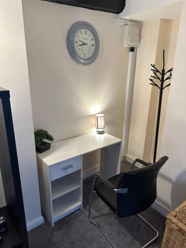 einen Schreibtisch mit einem Stuhl und einer Uhr an der Wand in der Unterkunft Comfort Zone in Colchester