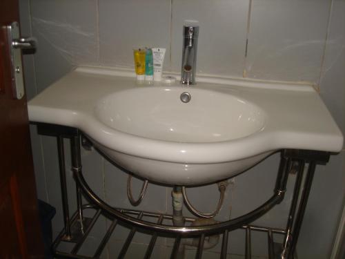 La salle de bains est pourvue d'un lavabo blanc et d'un robinet. dans l'établissement Acholi Inn, à Gulu
